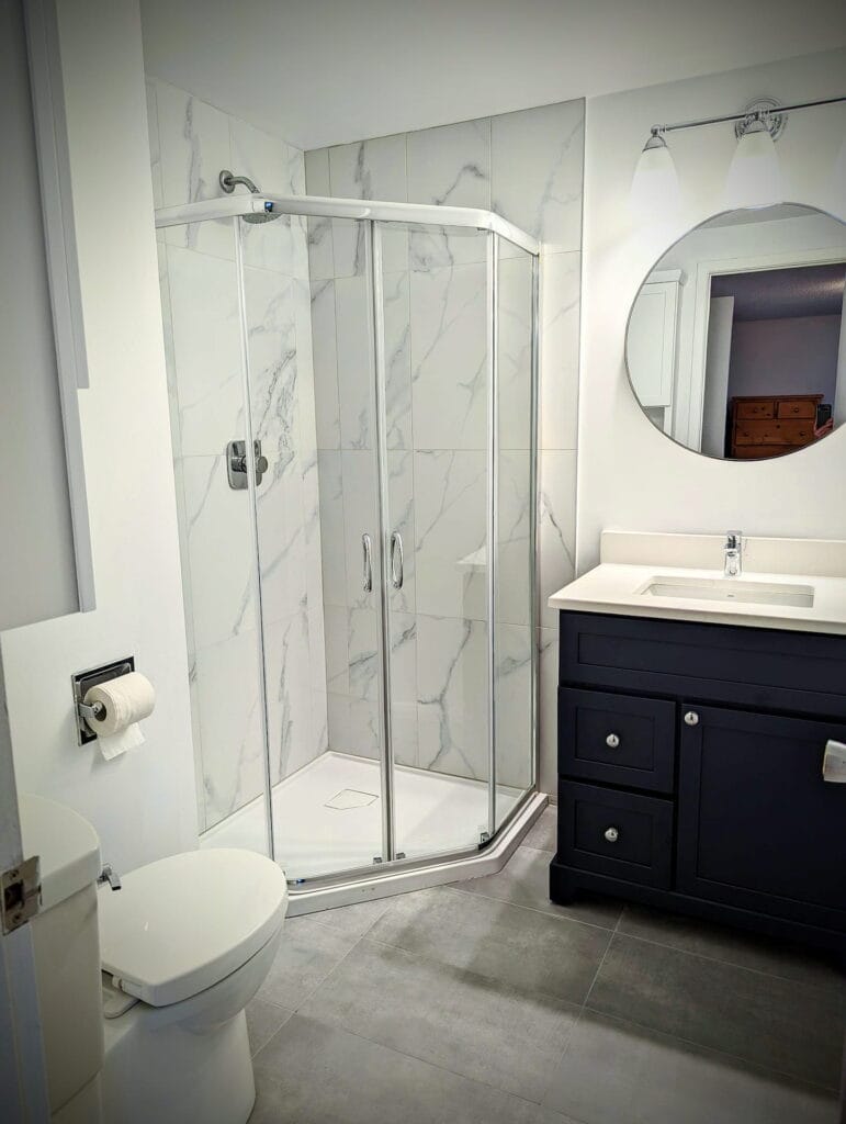 A spacious renovated bathroom in Arnprior with a stylish shower and toilet, highlighting a practical and inviting atmosphere.