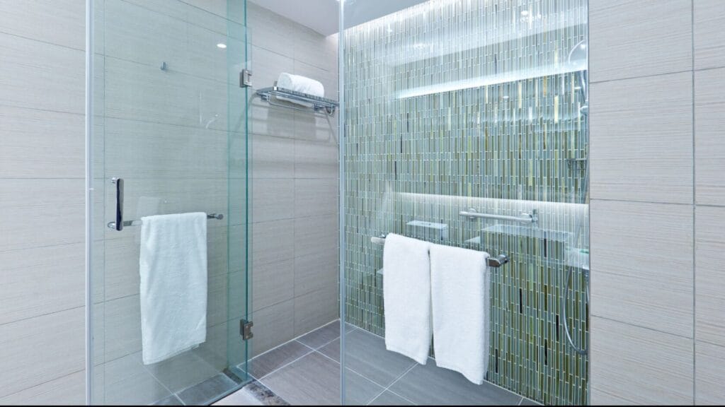A renovated bathroom in Orleans features a sleek glass shower door and a transparent glass wall, which enhances the spacious feel.